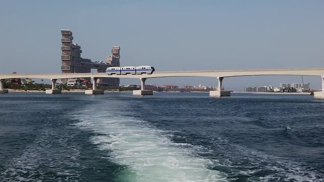 Palm Jumeirah scene showing Atlantis The Royal hotel and a moving monorail train traveling along the iconic island&rsquo;s elevated track. 