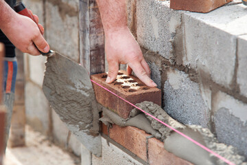 Close-up of skilled bricklayer working on construction site laying bricks for wall construction