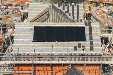 Aerial view from drone at construction workers installing solar panels on rroof of new house in...