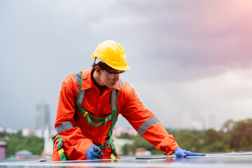 A man in a yellow helmet and orange jumpsuit is working on a roof