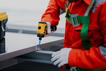 A man in a red jacket is working on a project, using a drill to make a hole