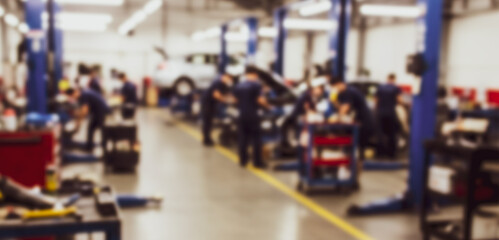 Auto repair shop with mechanics working on vehicles and equipment inside.