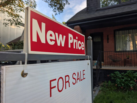 Sign for sale new price by detached house in residential area. Real estate market volatility,  bubble, crash, hot and cooling housing market, overpriced property, buyer activity concept.  