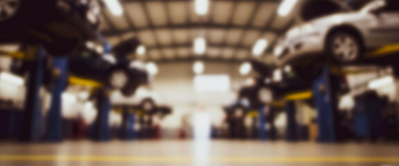 Cars on lifts in a repair shop interior with a blurred background.