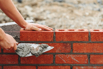 Close-up of skilled bricklayer working on construction site laying bricks for wall construction