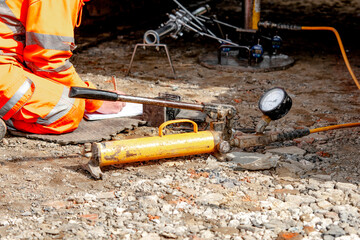 Geotechnical technician using gauges to perform California Bearing Ratio (CBR) test of the ground before works can continue on construction of new road