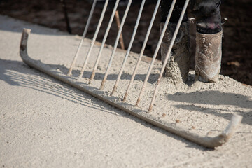 Close-up of Concreter leveling fresh concrete with screed dapple bar on building site