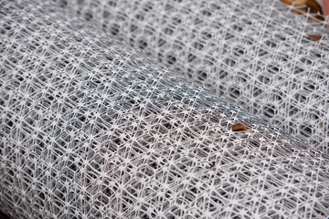 Close-up of the roll of white plastic geogrid mesh with intricate pattern and texture