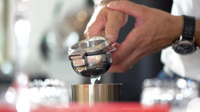 Close up of male bartender hands with watch that squeezing lime juice in metal hand squeezer. Drops fall into steel glass. Process of making and preparation alcoholic drink and cocktail in bar and pub