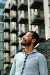 Businessman looking up at modern office building, contemplating future success