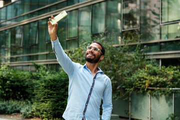 Young businessman taking selfie with smartphone in urban city setting
