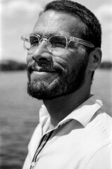 Bearded man wearing glasses smiling in monochrome analog film portrait