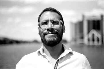 Smiling bearded man wearing glasses posing in black and white analog photo