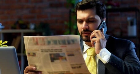 businessman reading business newspaper while sitting at modern computer desk, Indian Asian corporate executive focused on financial news, market updates, concept of awareness, leadership