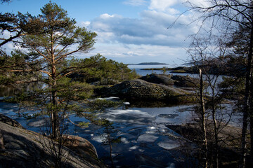 Skerries with growing trees, surrounded by the water surface of the lake and melting ice floes...