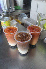 Iced Thai Milk Tea and Coffee Drinks Displayed on a Metallic Countertop. three layer tea or 3 layer coffee. Sarawak drink. borneo tea and coffee 3 layer. Three cups of iced beverages, featuring Thai m