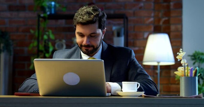 Businessman drafting email or typing on laptop sitting at office desk, Indian Asian corporate executive focused on communication, digital work, online correspondence, modern business productivity