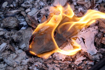 A hundred dollar bill is burning on a fire.