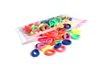 On a white background lies a transparent bag with multi-colored hair bands.