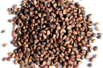 There is a pile of unpeeled pine nuts on a white background.