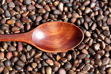 There is a wooden spoon with pine nuts.
