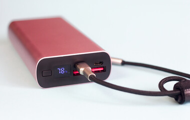 Powerbank with display showing battery charge percentage and cord to it close-up