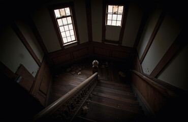 Obraz premium Dim spiral staircase with carved bannister in abandoned building.