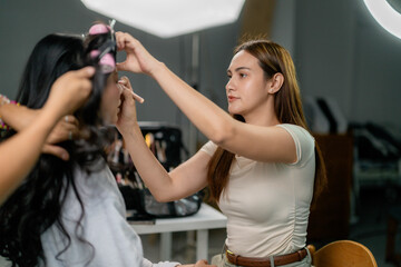 Makeup artist applying cosmetics on model face in professional studio