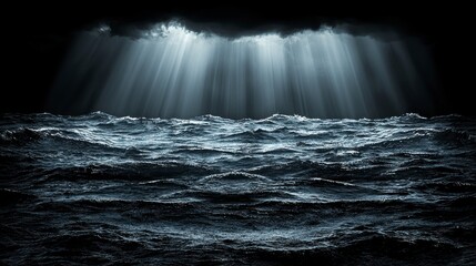 Dramatic beams light a stormy, dark, choppy ocean