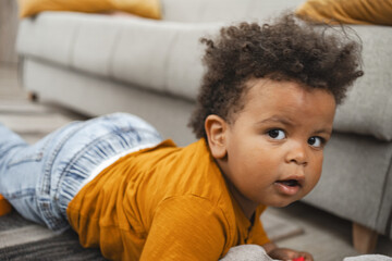 Multiracial toddler exploring a cozy living room on a soft rug