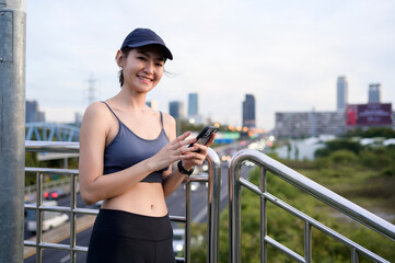 Woman Wearing Sports Attire Talks on Smartphone While Enjoying City Views During Sunset