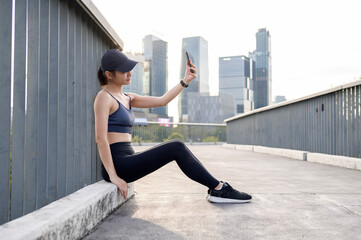 Woman Exercising Outdoors While Using a Smartphone in an Urban Environment During the Day