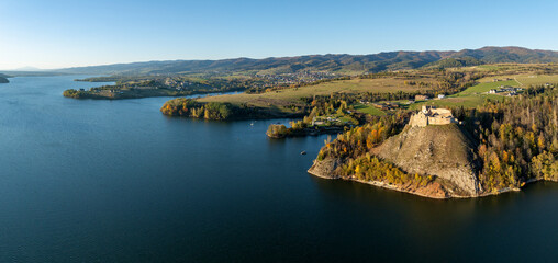 Poland. Wide aerial drone panorama of artificial Czorsztyn lake with gulfs and peninsulas, ruins of medieval Czorsztyn castle and Gorce mountain range in the background. Autumn colors, sunset light