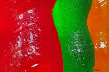 Close up of textured red green and orange surfaces with water droplets
