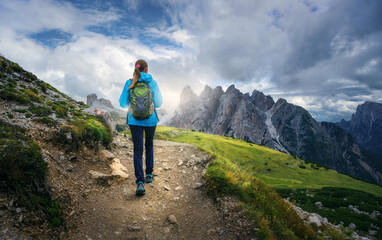 Young woman hiking along a mountain trail, carrying a backpack while savoring the breathtaking...