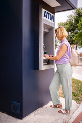 European traveler withdraws cash at an ATM in Greece