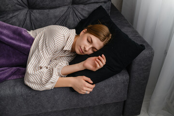 Young woman sleeping peacefully on gray sofa at home.