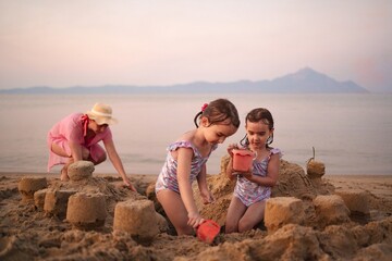 Joyful family building sandcastles on the beach at sunset