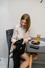 Black cocker spaniel puppy begging for food at breakfast table.