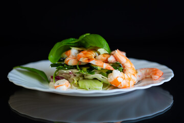 Appetizing salad with shrimps on a black background