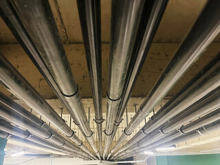 Overhead view of multiple black industrial pipes suspended beneath a concrete ceiling, illustrating complex utility systems and modern infrastructure for technical or construction designs