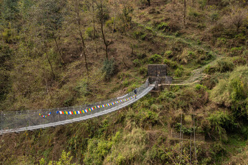 Rope bridge over the river in the jungle at the foot of Himalaya mountains in Nepal.