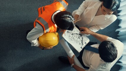 Top view of skilled architect engineer team looking at blueprint together. Aerial view of smart...