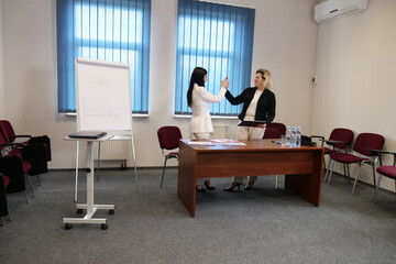Two women meet to discuss a project and sign a contract.