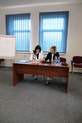 Two women meet to discuss a project and sign a contract.