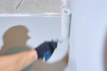 Close-up of a hand with a roller. Apartment renovation. Concrete walls are painted gray with a paint roller. High quality photo
