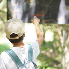 preteen boy on his back looking at the map of the mountain route he is following.