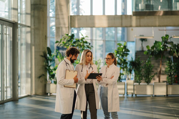 Medical team using digital tablet, discussing patient data in hospital lobby