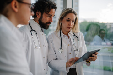 Medical team examining patient data on digital tablet in hospital