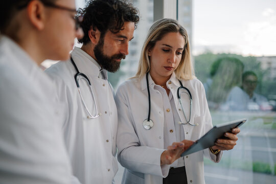 Medical team examining patient data on digital tablet in hospital